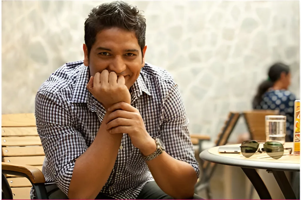 Abhishek Mittal, a man resting his chin on his hands at a café table